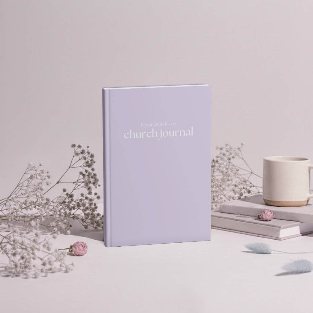 Purple church journal on a light surface with flowers and a mug in the background