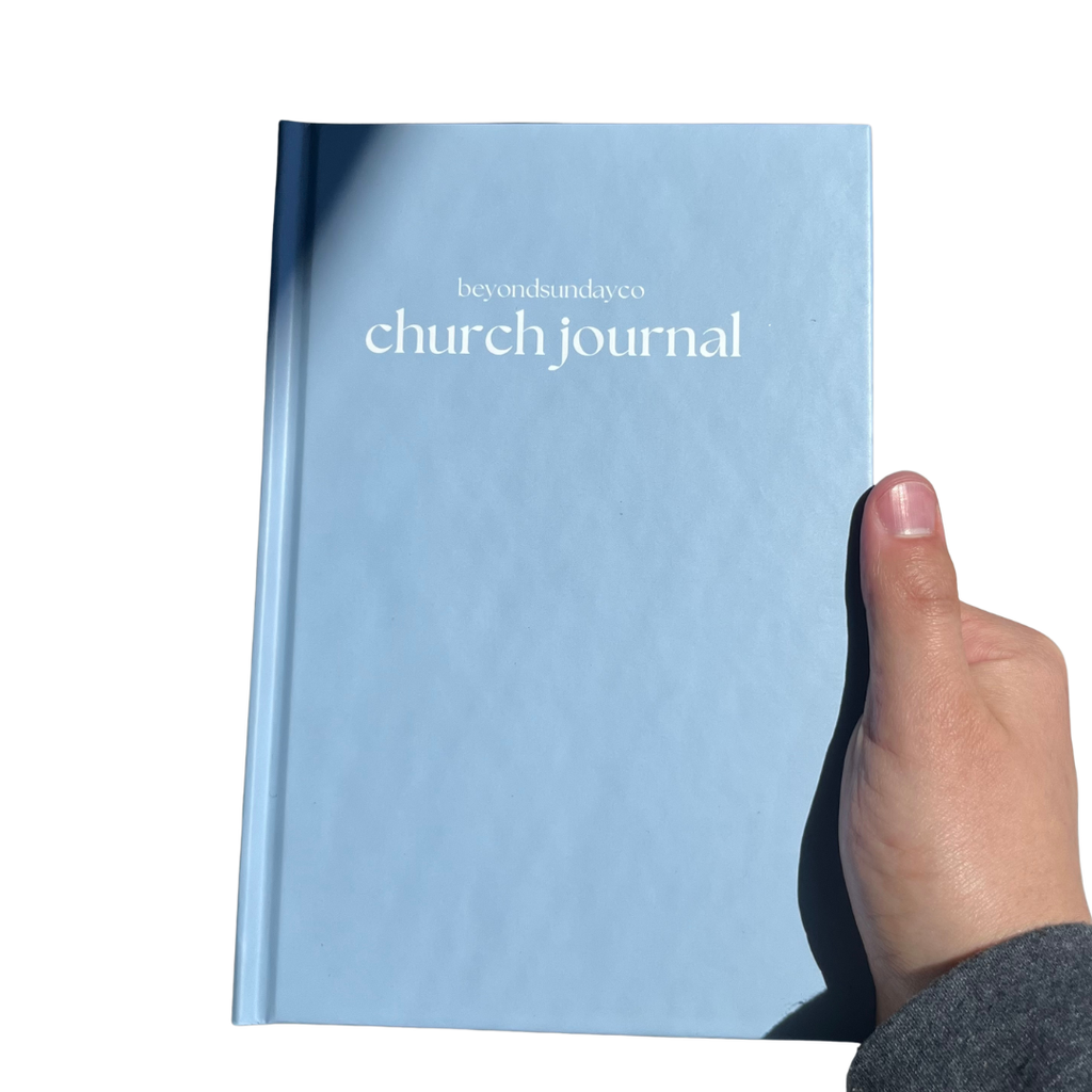 Light blue 'church journal' held by a hand on a white background