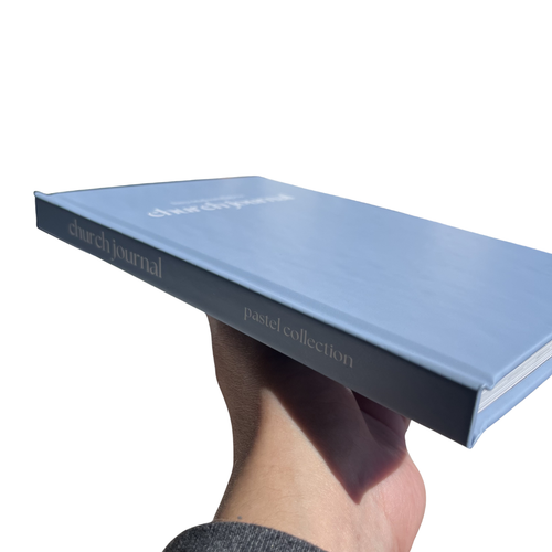 Hand holding a blue journal titled 'Pastel Collection' on a white background