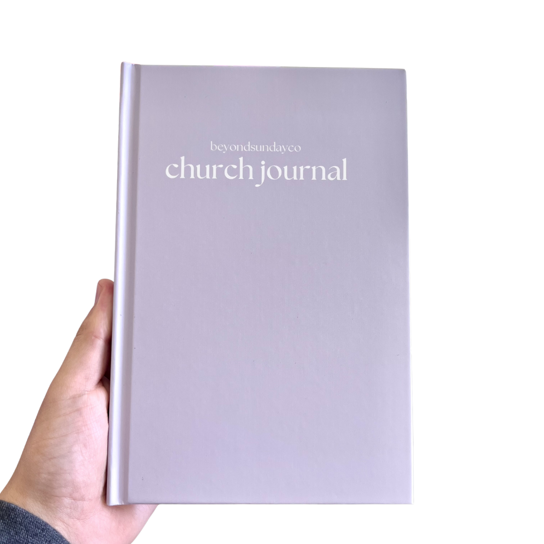 Hand holding a purple 'church journal' with 'beyond sunday co' branding on a white background